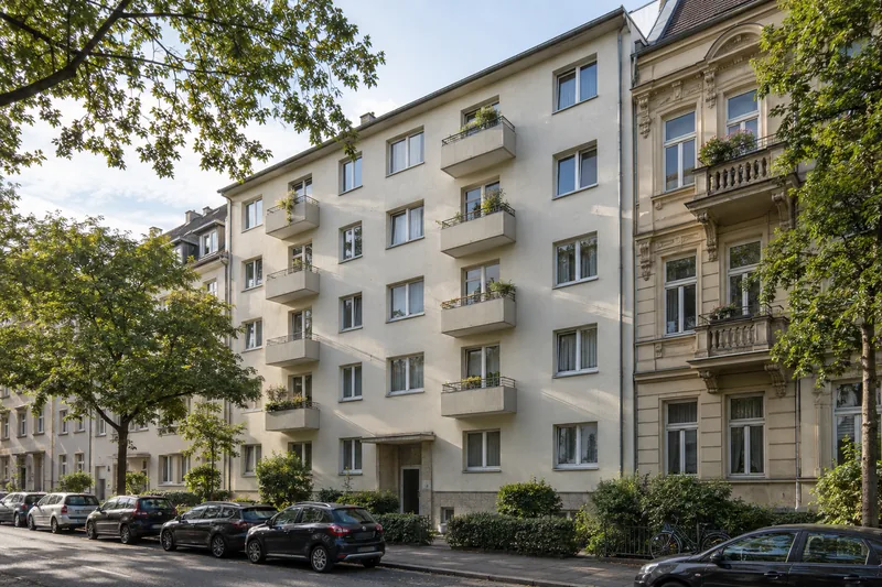 Badsanierung in der Mietwohnung: Mehrfamilienhaus der 1950er-Jahre mit heller Putzfassade neben einem Altbau